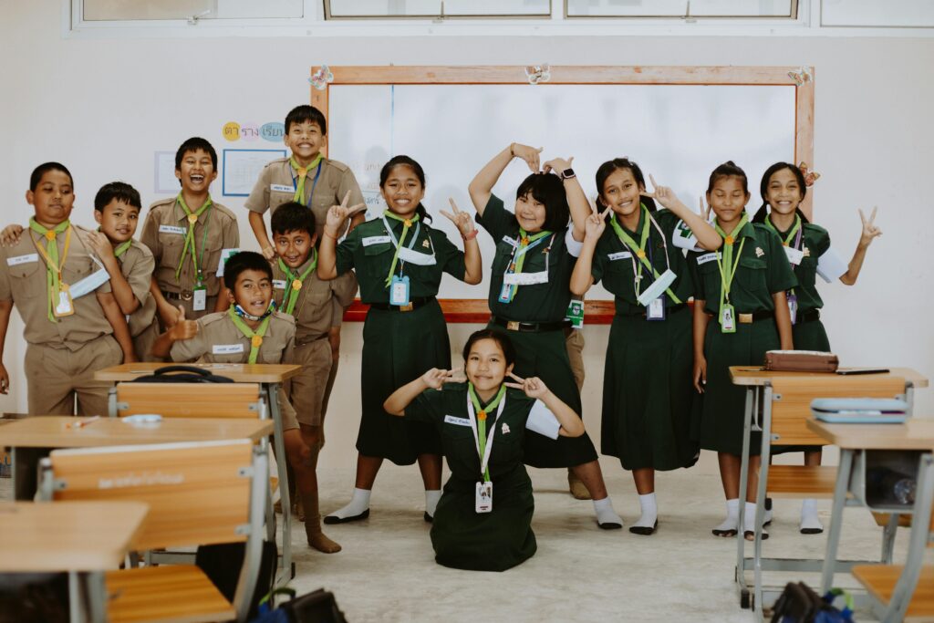 Group of Thai students in uniform posing happily in their classroom, reflecting friendship and joy.