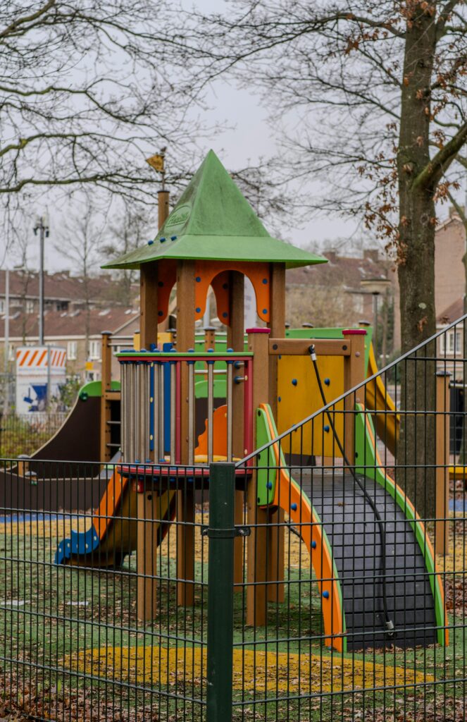 Vibrant playground equipment surrounded by trees in a park in Amsterdam.