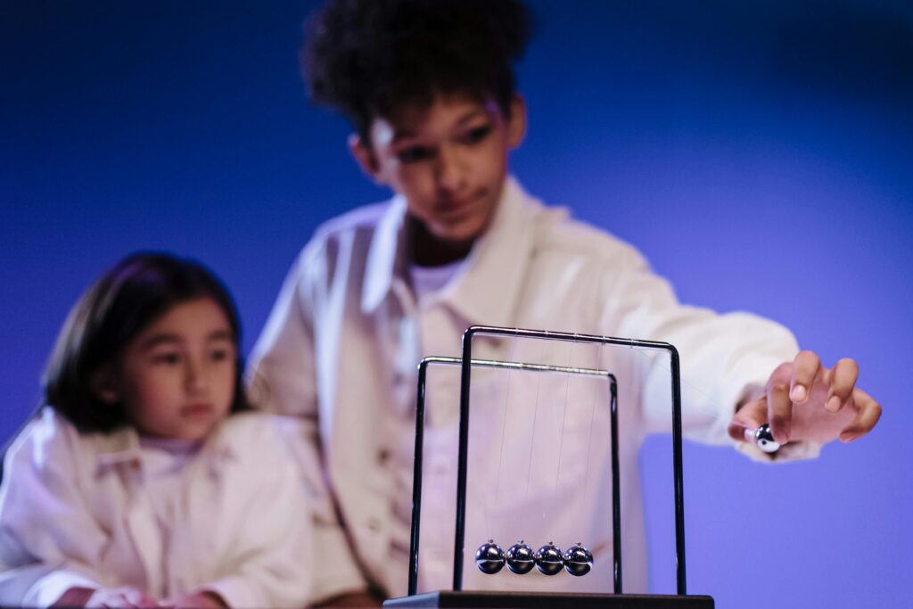 Engaged children learning physics through hands-on play with Newton's Cradle.